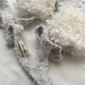 Close-up van de fluffy gebreide sjaal textuur met zachte witte pompons detail ontwerp.