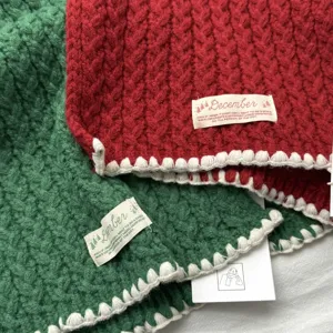 Gros plan detaille de l'echarpe de noel en tricot cable coreen en rouge et vert bordure.
