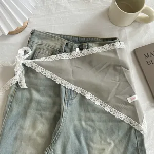 Gedetailleerd uitzicht van een transparante grijze overslagdoek met subtiele witte kant.