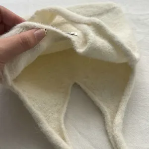 Vue détaillée du sac à main en tricot de laine duveteux, texture douce et souple, tissu crème.