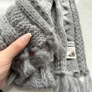 Winterlicher warmer grauer Strickschal mit Fransen und süßem Label-Detail für Damen.
