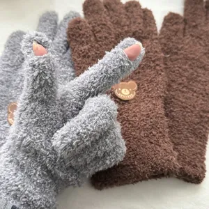 Close-up detail of fuzzy fleece winter gloves with cute bear patch and fingerless design.