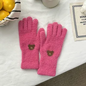 Plush pink winter gloves detail shot, cute bear patch design, soft warm coral fleece texture.