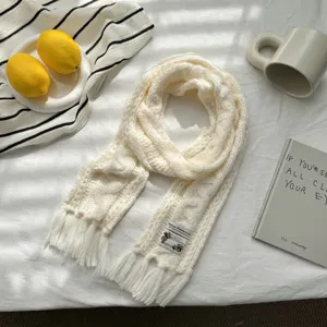 Detailansicht des weichen weißen Strickschals mit klassischem Zopfmuster und Fransen.