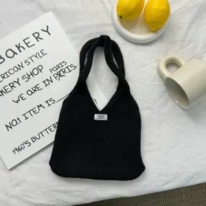 Vue détaillée du sac cabas en tricot noir avec design minimaliste et texture douce.