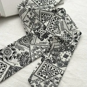 Gedetailleerd overzicht van zwart-witte paisley print twilly sjaal, haarband textuur.