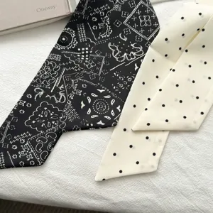 Detailopname van smalle sjaals met zwart paisley- en crèmekleurig polka-dot-patroon.