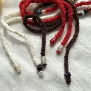 Vue détaillée de colliers et bracelets en laine tricotée faits main avec des perles colorées.