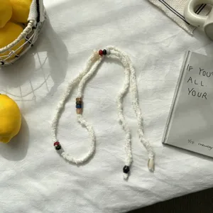 Vue détaillée d'un collier-sautoir en maille blanche avec perles colorées, style rétro chic.