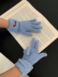 Detailed shot of cute blue knitted gloves with puppy embroidery, touch screen design for winter warmth.