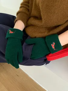 Detailed shot of dark green knit gloves with cute puppy embroidery, cozy winter warmth.