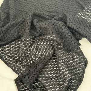 Détail de foulard triangulaire texturé noir ajouré, tour de cou d'été respirant.