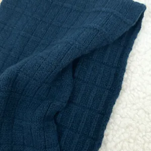 Close-up detail of dark blue knitted winter scarf, soft wool texture, cozy and warm style.