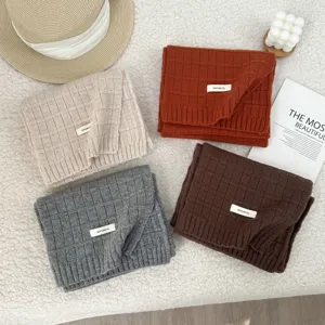 Detailed view of cozy 100% wool knit scarves in multiple colors with grid pattern texture.