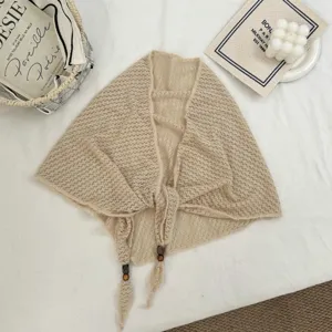 Détail d'écharpe triangulaire en tricot beige, texture respirante, perles en bois, rétro.