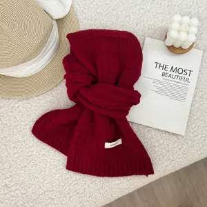 Detail view of soft red knitted wool scarf featuring delicate plaid texture and cozy warm feel.