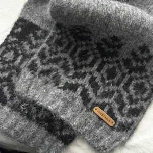 Sciarpa invernale morbida grigia con motivo geometrico ed elegante etichetta in pelle.