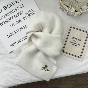 Detailed view of white knitted scarf with embroidered horse design, soft and warm texture.