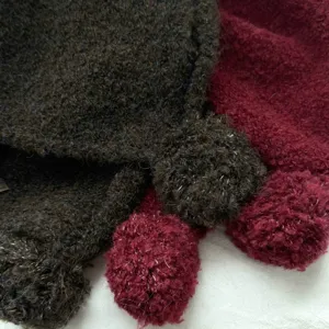 Close-up detail of the fuzzy wool knit balaclava hat, showing soft boucle texture and pom-poms.