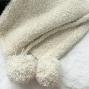 Close-up detail of fluffy wool-blend balaclava hat with cute pom-poms, warm winter knit.