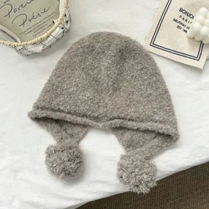 Detailed view of the cozy wool-blend balaclava with cute pom-pom earflaps and soft texture.