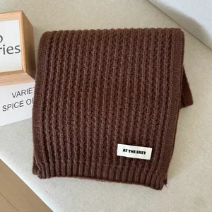 Brown knit scarf detail shot, showing soft ribbed woolen texture for winter warmth.