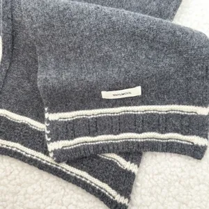 Close-up of dark grey knitted wool scarf detail with white stripes, soft winter accessory.