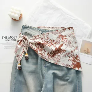 Detail view of retro floral waist wrap strap skirt layered with denim jeans aesthetic flat lay.