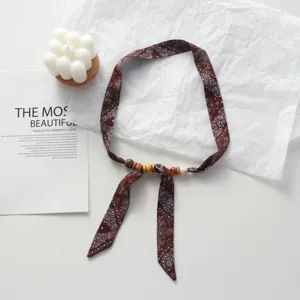 Close-up detail of bohemian paisley print fabric necklace with wooden beads and adjustable tie.