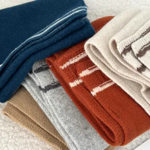 Closeup view of colorful knitted winter scarves stacked together with soft cozy texture.