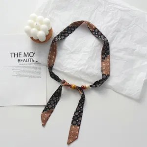 Close-up detail of a floral fabric ribbon necklace featuring decorative wooden beads.