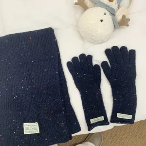 Close-up of dark blue knit scarf and gloves set with colorful flecks, cozy autumn winter style.
