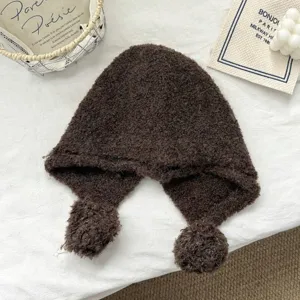 Close-up detail of dark brown wool blend balaclava hat with cute ear flaps and pom-poms.