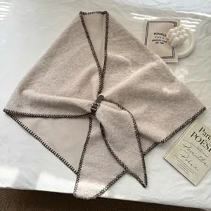 Vue détaillée du châle triangulaire en tricot avec bord contrasté et boucle en cuir.