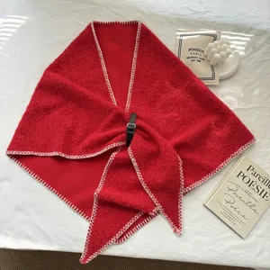 Détail d'écharpe triangulaire rouge en tricot avec coutures blanches et boucle en cuir noir.