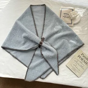 Détail châle triangulaire duveteux bleu tricoté, bords contrastés marron et boucle en cuir.
