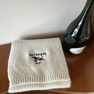 Detalle de bufanda de punto suave con un lindo bordado de salchicha y textura cálida.