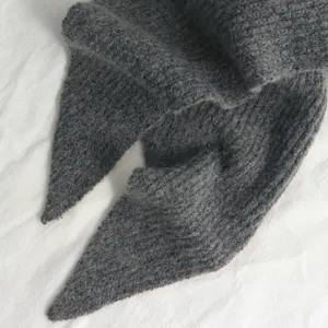Vue détaillée de l'écharpe d'hiver en tricot gris foncé et de son joli bonnet chaud.