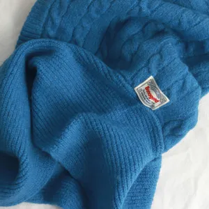 Détail de cagoule bonnet écharpe tricotée d'hiver bleue, vêtement chaud douillet avec étiquette.