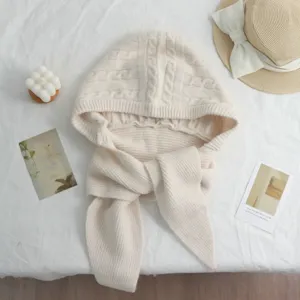 Vue détaillée de la cagoule tricotée blanc cassé avec un design d'écharpe intégrée.