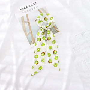 Detalle de bufanda de gasa con estampado de kiwi verde brillante sobre tela blanca.