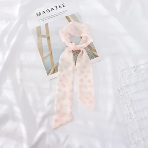 Dettaglio di nastro per capelli in chiffon con stampa floreale rosa e design elegante.