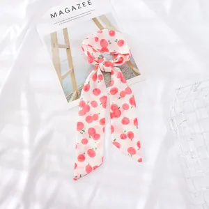 Detalle de primer plano de una bufanda de cinta de gasa con estampado de cerezas, accesorio chic.