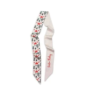Vue détaillée du foulard en soie imprimé mince, avec des motifs délicats de feuilles et de fleurs.