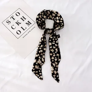 Vue de détail en gros plan du foulard en ruban de soie imprimé floral noir et blanc, texture douce.