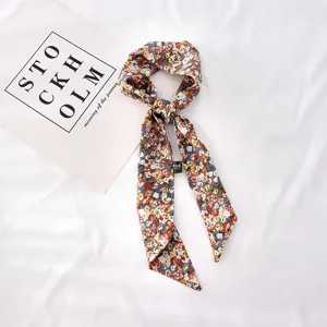 Détail de foulard à motif floral avec une texture de tissu fine et ruban élégant.