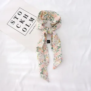 Gros plan détaillé d'un foulard en soie à imprimé floral, accessoire élégant pour cheveux ou poignet.
