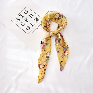 Détails de l'écharpe fine à fleurs jaunes, ruban pour cheveux et accessoire chic.