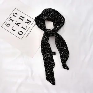 Élégant foulard en soie noir et blanc moucheté, parfait pour coiffure ou accessoire de poignet.