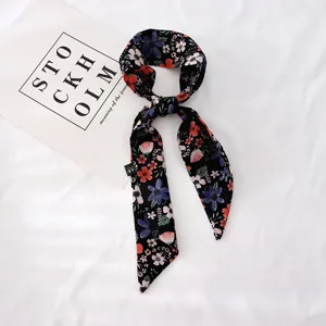 Vue détaillée d'un foulard en soie à fleurs noires, idéal pour cheveux ou poignet.